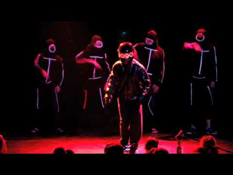 A frame from the video showing the helmeted protagonist and backup dancers